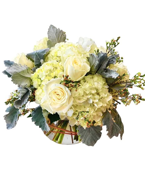 Fresh cut hydrangeas and roses in shades of green and white in a bubble bowl vase